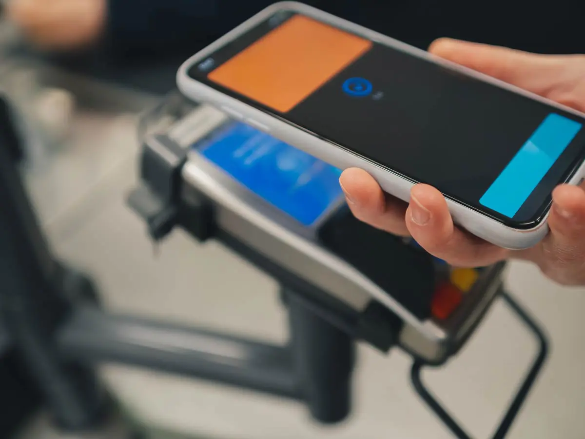 A person holding their phone over a payment terminal